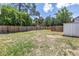 Back yard surrounded by a wood fence, grassy lawn and mature trees at 750 49Th N Ave, St Petersburg, FL 33703