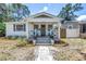 Charming home featuring a covered front porch with blue chairs and a well-maintained landscaped yard at 750 49Th N Ave, St Petersburg, FL 33703