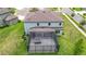 Aerial view of a home's backyard features screened in lanai and lush green lawn at 7628 Surf Reed Way, Wesley Chapel, FL 33545