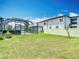 Backyard features a screened lanai, green lawn and privacy fence, creating a private outdoor oasis at 7628 Surf Reed Way, Wesley Chapel, FL 33545