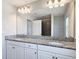 Bathroom featuring a double sink vanity with granite counters and modern lighting at 7628 Surf Reed Way, Wesley Chapel, FL 33545