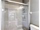 Tiled shower enclosure with glass doors and chrome fixtures, and a view into the kitchen at 7628 Surf Reed Way, Wesley Chapel, FL 33545