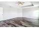Bright primary bedroom features wood-look flooring, a ceiling fan, and ample natural light at 7628 Surf Reed Way, Wesley Chapel, FL 33545