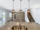 Open-concept living space featuring a kitchen island with granite countertops and pendant lighting at 7628 Surf Reed Way, Wesley Chapel, FL 33545