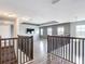 Spacious upstairs loft with modern flooring and dark wood railings with an installed television at 7628 Surf Reed Way, Wesley Chapel, FL 33545