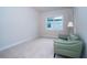 Neutral bedroom with a soft green chair and large window providing natural light at 8834 Sanders Tree Loop, Wesley Chapel, FL 33545