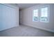 Empty bedroom with two windows, closet, neutral carpet, and baseboards, awaiting your personal touch at 8834 Sanders Tree Loop, Wesley Chapel, FL 33545
