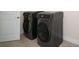 Modern laundry room with a pair of charcoal gray front load washer and dryer at 8834 Sanders Tree Loop, Wesley Chapel, FL 33545