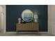 Hallway with a stylish console table, round mirror, and decorative accessories against a navy blue wall at 9456 Gladsome Dr, Land O Lakes, FL 34637