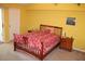 Bright bedroom featuring a wooden bed frame, soft carpet, and sunny yellow walls at 9722 Indian Key Trl # 116, Seminole, FL 33776