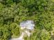 Birds eye view of the home with its silver roof nestled among vibrant green trees at 1562 Oakhurst Dr, Brooksville, FL 34601