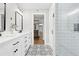 Bathroom with double sinks, walk-in shower, decorative floors, and a view of stairs to the lower level at 1562 Oakhurst Dr, Brooksville, FL 34601