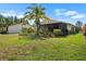 Backyard featuring a well-manicured lawn and tropical landscaping at 1762 Atrium Dr, Sun City Center, FL 33573