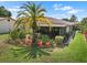 Inviting backyard featuring mature palm trees, colorful flowerbeds, and a screened lanai, ideal for relaxing outdoors at 1762 Atrium Dr, Sun City Center, FL 33573