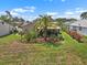 Landscaped backyard showcasing vibrant flowerbeds, a mature palm tree, and a screened lanai, perfect for outdoor living at 1762 Atrium Dr, Sun City Center, FL 33573