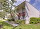 Townhouse exterior with green grass and a sidewalk leading up to the front door at 1877 Pine Cone Cir, Clearwater, FL 33760