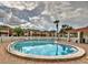 Community outdoor pool features a brick border, ample sunlight, lounge furniture, and a charming covered cabana at 1877 Pine Cone Cir, Clearwater, FL 33760