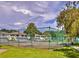 Community tennis court behind a chain link fence with a view of the townhomes beyond at 1877 Pine Cone Cir, Clearwater, FL 33760