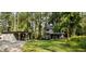 Exterior view of the charming home with a detached garage and spacious green lawn surrounded by trees at 22004 Dupree Dr, Land O Lakes, FL 34639