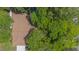 Aerial view of a home with a brown shingle roof surrounded by lush green trees and a swimming pool at 2285 Hidden Meadows E Dr, Palm Harbor, FL 34683