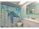 Bright bathroom features a whimsical shower curtain, white vanity, and ample lighting at 2285 Hidden Meadows E Dr, Palm Harbor, FL 34683