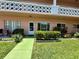 A condo's welcoming entrance featuring a green walkway, small seating, and well-maintained landscaping at 2457 Ecuadorian Way # 27, Clearwater, FL 33763