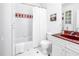 Bright bathroom with a shower-tub combo, white tiling, and red vanity at 2710 10Th N St, St Petersburg, FL 33702
