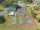 Aerial view featuring the community clubhouse and pool, along with tennis, basketball, and shuffleboard courts amid lush surroundings at 3642 Fantasy Way, Brooksville, FL 34604