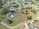 Wide aerial view of the community clubhouse, pool, tennis, basketball, and shuffleboard courts among manicured lawns and homes at 3642 Fantasy Way, Brooksville, FL 34604