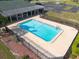 Aerial view of the community pool surrounded by lush landscaping, a black fence, and lounge chairs for residents at 3642 Fantasy Way, Brooksville, FL 34604