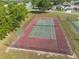 Aerial view of a red and green fenced community tennis court bordered by a green treeline in a residential neighborhood at 3642 Fantasy Way, Brooksville, FL 34604