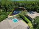 Aerial view of the property featuring a screened pool, pond and lush greenery at 3910 Saywood Ct, Palm Harbor, FL 34685