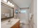 Well-lit bathroom features a wooden vanity, a decorative mirror, and a shower-tub combo with neutral tile at 3910 Saywood Ct, Palm Harbor, FL 34685