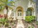 Charming home entrance with manicured landscaping, mature palm trees, and elegant archway at 3910 Saywood Ct, Palm Harbor, FL 34685