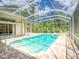Inviting screened-in pool and spa with brick paver deck and lush landscaping at 3910 Saywood Ct, Palm Harbor, FL 34685