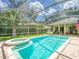 Screened-in pool and spa area with brick pavers and views of the backyard and landscaping at 3910 Saywood Ct, Palm Harbor, FL 34685