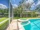 Sparkling pool and spa surrounded by a screened enclosure and brick pavers, offering a private backyard oasis at 3910 Saywood Ct, Palm Harbor, FL 34685