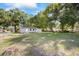 Wide shot of the house from the yard with a large grassy area surrounded by shady trees at 4804 N 18Th St, Tampa, FL 33610