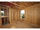 Upstairs bedroom under construction with framing and plywood walls, with a view of backyard trees at 503 W Warren Ave # 1, Tampa, FL 33624