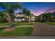 Twilight shot of a two-story home, with landscaped yard and mature palm trees at 5057 Ivory Stone Dr, Wimauma, FL 33598