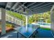 Covered outdoor patio with ping pong table, stairs to second story, and view of pool area at 540 Gulf Bay Rd, Longboat Key, FL 34228