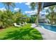 Serene backyard pool and lounge area framed by tropical landscaping, complete with a poolside bar for relaxing at 540 Gulf Bay Rd, Longboat Key, FL 34228