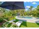 Backyard pool with sun loungers, artificial turf, and umbrella; perfect for relaxation and outdoor entertainment at 540 Gulf Bay Rd, Longboat Key, FL 34228