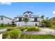 Beautiful two-story home featuring lush landscaping, a symmetrical staircase entryway, and distinctive black and white accents at 6024 Kipps Colony E Dr, Gulfport, FL 33707