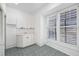 Bright laundry room area with washer/dryer hookups, a sink, storage cabinets and window with white shutter blinds at 6024 Kipps Colony E Dr, Gulfport, FL 33707