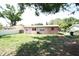 The backyard features a grassy area and the rear of the home with windows at 6508 Los Altos Way, Tampa, FL 33634