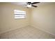 Bright bedroom features neutral tile floor, ceiling fan and window letting in natural light at 6514 La Mesa Cir, Tampa, FL 33634