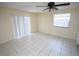 Neutral bedroom with tiled floors features a ceiling fan, a window and sliding glass door for natural light at 6514 La Mesa Cir, Tampa, FL 33634