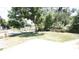 View of the lawn, mature trees, and chain link fence enclosing the front yard of the property at 6514 La Mesa Cir, Tampa, FL 33634