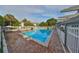 Bright pool surrounded by brick with lounge chairs, tables, palm trees, and white fences underneath a partly cloudy sky at 776 116Th N Ave # 1110, St Petersburg, FL 33716